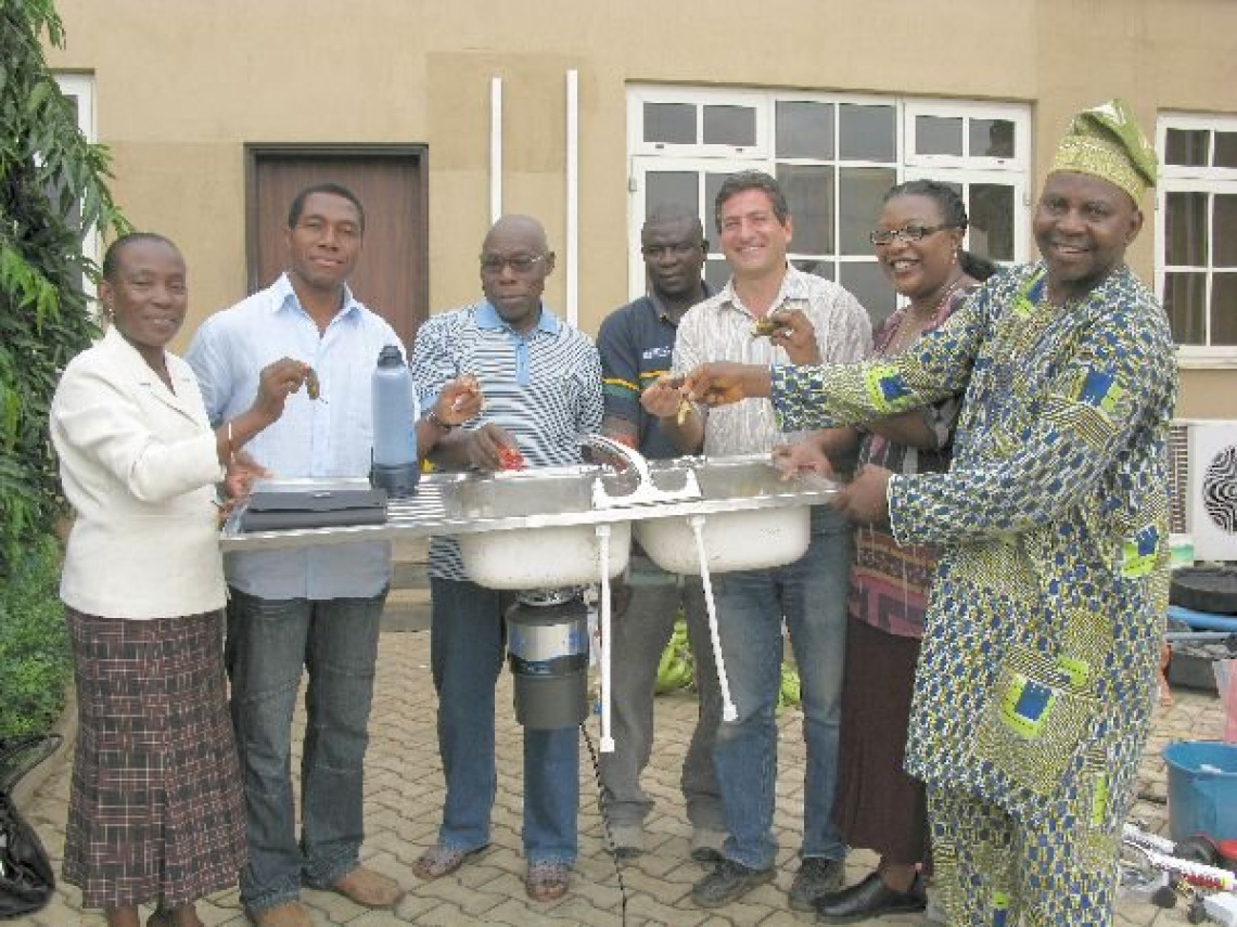 Former Nigerian President Oluwasegun Obasanjo demonstrates the Insinkerator Food Waste Grinder that Emerson Electronics gave him as a gift to use with his home biodigester.