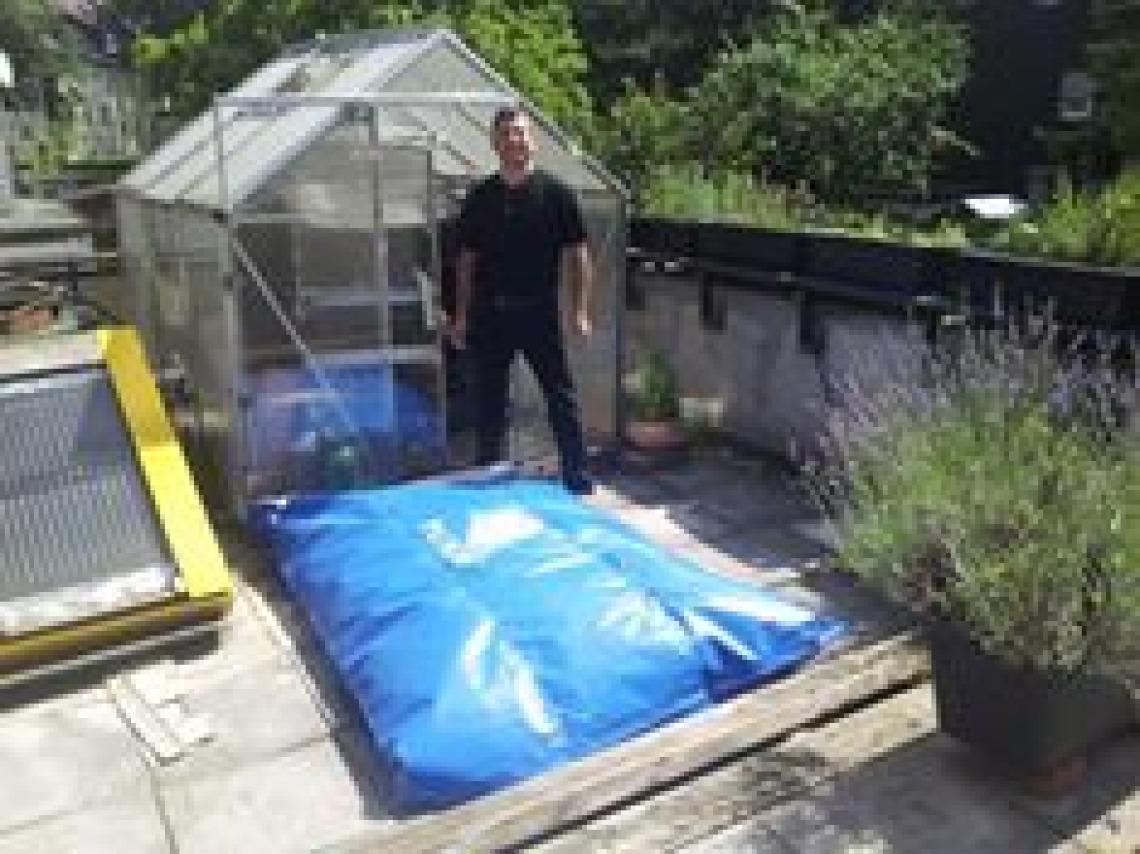 One of Culhane's biodigesters (in the greenhouse behind him) feeding a 1000 liter Puxin biogas bag.